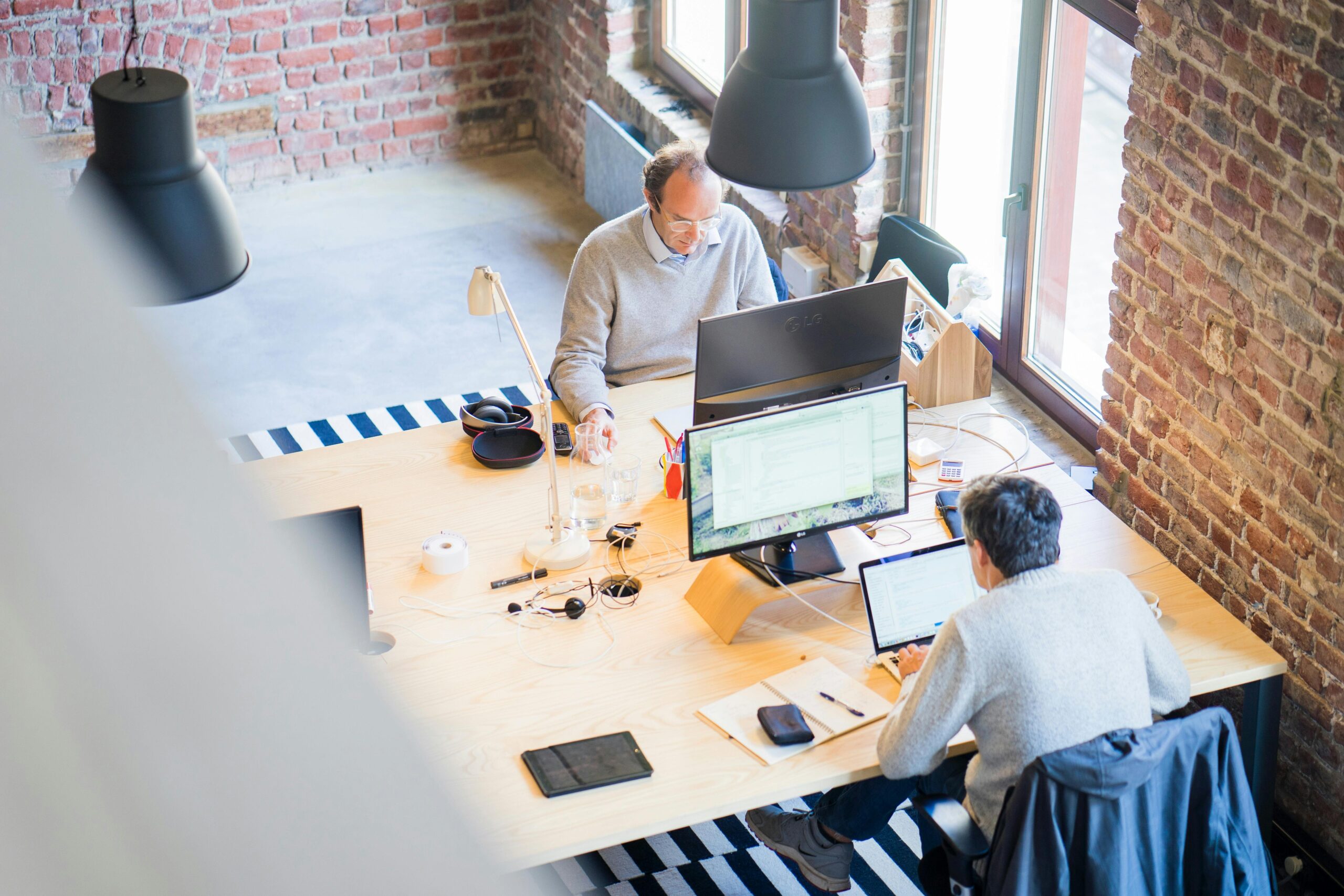 pexels-photo-2451646-2451646-2 Bird's-eye view of a modern office with professionals collaborating on laptops and monitors.